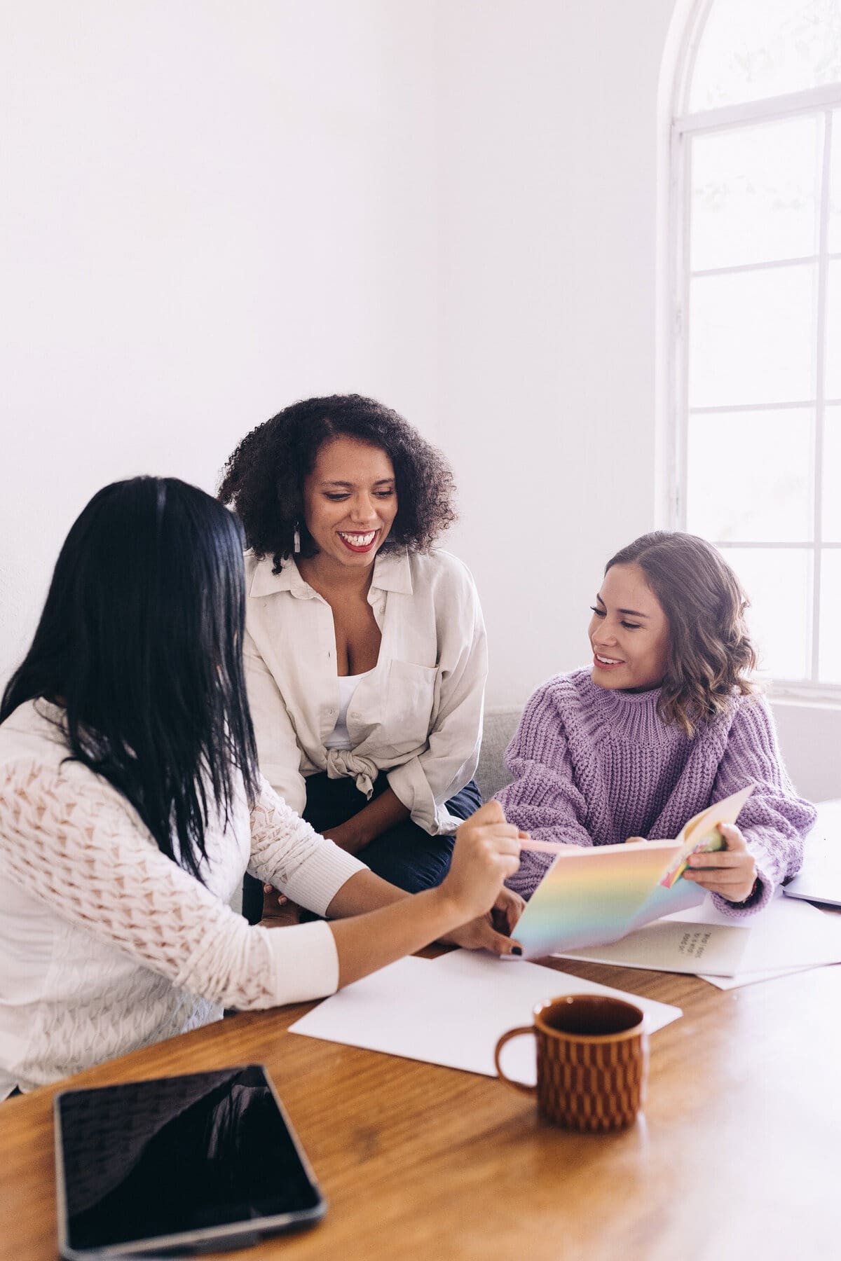 Women sit together and discuss the difference between a business coach and a business strategist